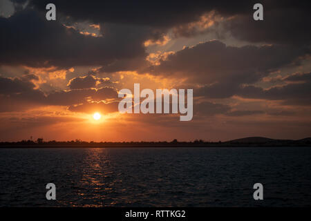 Dramaitc Sonnenuntergang und Sonnenstrahlen durch die Wolken am Strand peaking Stockfoto