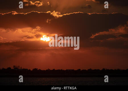 Dramaitc Sonnenuntergang und Sonnenstrahlen durch die Wolken am Strand peaking Stockfoto