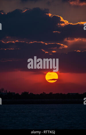 Dramaitc Sonnenuntergang und Sonnenstrahlen durch die Wolken am Strand peaking Stockfoto