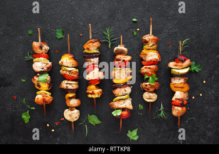 Mit gegrilltem Gemüse und hähnchenspieße mit Paprika, Zucchini, Zwiebel und Pilze auf schwarzen Hintergrund, Ansicht von oben. Fleisch und Gemüse Kebabs auf s Stockfoto
