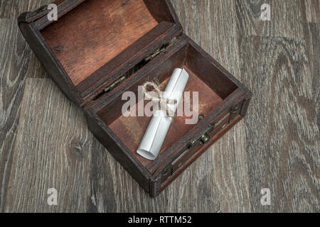 Verknittertes Papier und gebunden mit einer Schnur mit einer Nachricht in einem alten offenen Brustkorb Stockfoto
