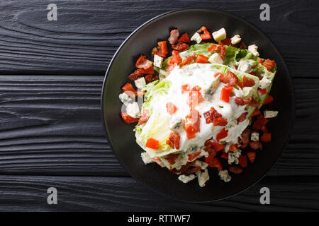 Amerikanische Keil Salat mit Eisbergsalat, Blue Cheese Dressing, knusprigen Speck und frischen Tomaten closeup auf einem Teller auf den Tisch. horizontal oben vie Stockfoto