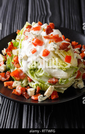 Classic Wedge Salat mit einem Stück Eisbergsalat, Tomaten, roten Zwiebeln, Speck und hausgemachten Blue Cheese Dressing closeup auf einem Teller auf den Tisch. Ver Stockfoto