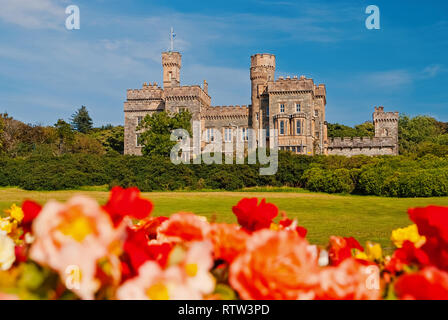 Lews Castle in Stornoway, Großbritannien mit unscharfen Rosen im Vordergrund. Schloss mit grüne Gelände am blauen Himmel. Historische Architektur und Design. Sehenswürdigkeiten und Attraktionen. Sommer Urlaub auf der Insel. Stockfoto