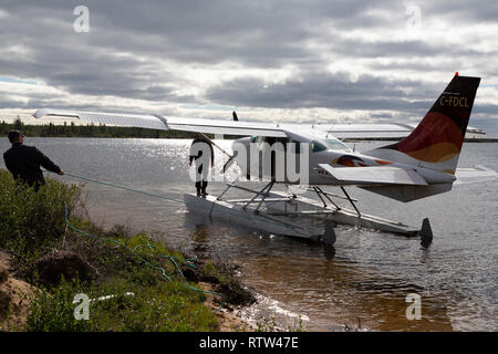 Piloten Halteband ein Wasserflugzeug auf einem See in Manitoba, Kanada. Das Flugzeug hebt ab und landet auf dem Wasser. Stockfoto