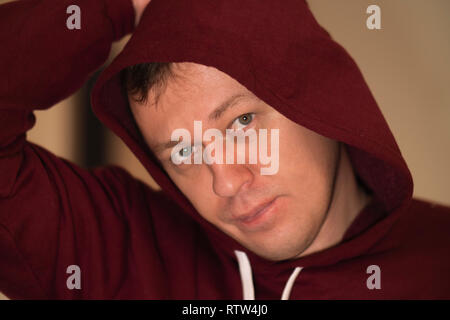 Porträt eines jungen Mannes in einer Haube, in die Kamera schaut, close-up Stockfoto