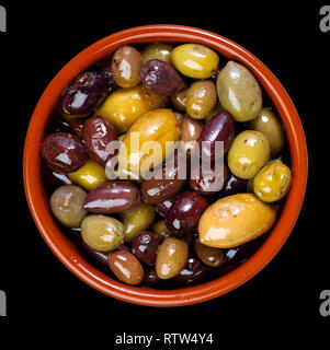 Grün und Lila, gemischte Oliven in Ton Schüssel - auf schwarzem Hintergrund Stockfoto
