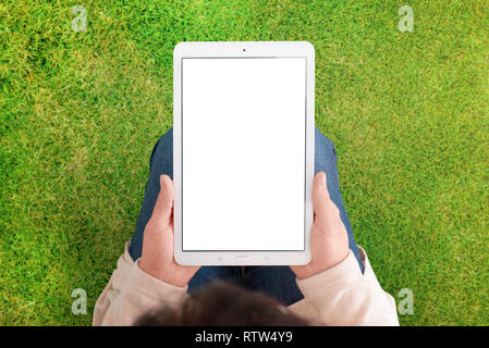 Tablet mockup mit grünem Gras, Wiese im Hintergrund. Frau halten weiße Tablette mit isolierten Bildschirm in vertikaler Stellung. Weißen, leeren Bildschirm für App. o Stockfoto