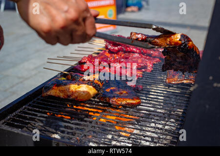 Schweinefleisch Kebabs und Huhn an einem Lebensmittelmarkt in Christchurch Square für Philippinen Tag gegrillt werden Stockfoto