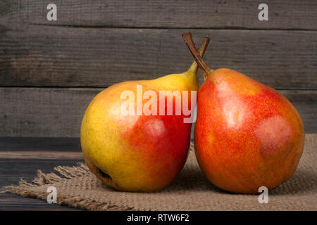 Zwei ganze und halbe der Birne auf einem Holztisch mit Tuch Leinwand Stockfoto