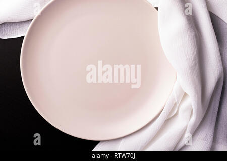 Beige leeren Teller mit weißen Küchentuch auf dunklen Tisch. Freier Speicherplatz für Inschriften und Design. Stockfoto