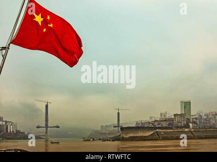 Stadt Chongqing, China. 22 Okt, 2006. Die rote Flagge von China fliegt vom Heck eines Schiffes in den Jangtse Framing, durch den Nebel, eine Brücke über den Fluss in Chongqing Gemeinde gebaut wird. Credit: Arnold Drapkin/ZUMA Draht/Alamy leben Nachrichten Stockfoto