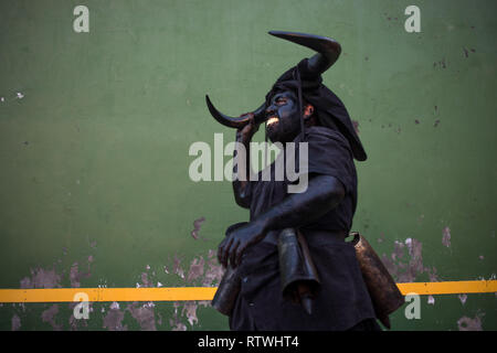 Ein Mann ist, kleiden sie sich wie ein Teufel während der Teufel von Luzon Karneval gesehen. Hunderte von Menschen aus der alten Tradition des Festivals der Teufel und die maskierten Figuren zu feiern. Leute kleiden wie Teufel mit Stier Hörner, Kuhglocken und Malen thei Körper mit schwarzen Öl und Ruß. Nachtschwärmer tragen weiße Masken. Die Tradition geht zurück bis in das 14. Jahrhundert. Stockfoto