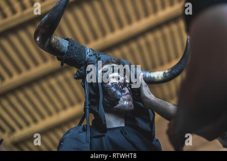 Ein Nachtschwärmer ist, mit Öl und Ruß während der Teufel von Luzon Karneval. Hunderte von Menschen aus der alten Tradition des Festivals der Teufel und die maskierten Figuren zu feiern. Leute kleiden wie Teufel mit Stier Hörner, Kuhglocken und Malen thei Körper mit schwarzen Öl und Ruß. Nachtschwärmer tragen weiße Masken. Die Tradition geht zurück bis in das 14. Jahrhundert. Stockfoto