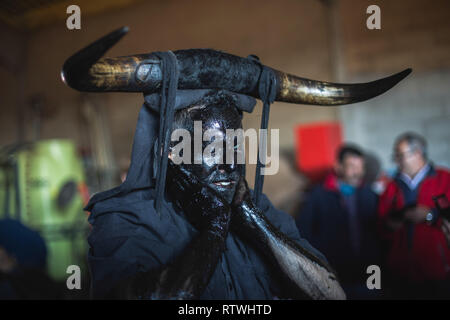 Ein Nachtschwärmer ist, mit Öl und Ruß während der Teufel von Luzon Karneval. Hunderte von Menschen aus der alten Tradition des Festivals der Teufel und die maskierten Figuren zu feiern. Leute kleiden wie Teufel mit Stier Hörner, Kuhglocken und Malen thei Körper mit schwarzen Öl und Ruß. Nachtschwärmer tragen weiße Masken. Die Tradition geht zurück bis in das 14. Jahrhundert. Stockfoto