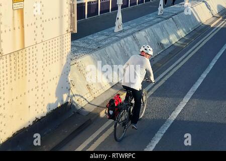 Ein Mann auf dem Fahrrad und Chelsea Bridge in London, Großbritannien Stockfoto