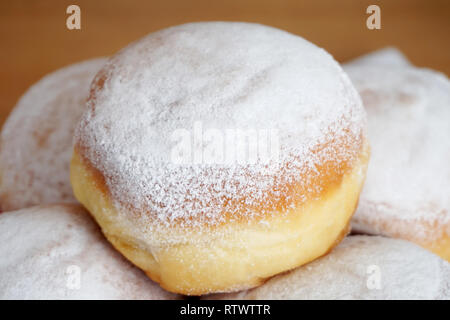 Leckere süße Nachspeise aus Sauerteig in Pulverform mit weißen Zucker. Mit leckeren Krapfen mit einem auf der oberen Platte Stockfoto