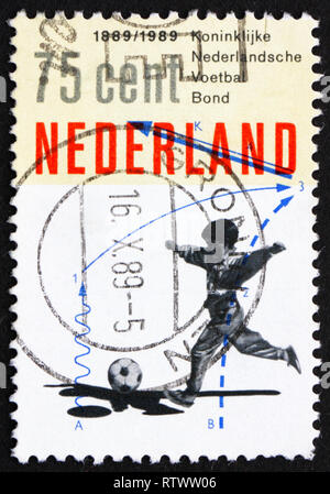 Niederlande - ca. 1989: einen Stempel in den Niederlanden gedruckten zeigt Junge spielt Fußball, 100-Jahrfeier der Royal Dutch Soccer Association, ca. 1989 Stockfoto