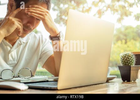 Business Mann depression Arbeiten am Laptop mit Hand seinen Kopf Stockfoto