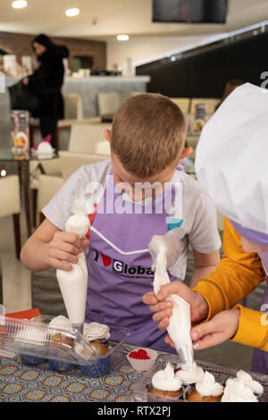 Kinder lernen kleine Kuchen mit Sahne zu kochen. Machen einen Urlaub Karte für Mama. März 8. Stockfoto