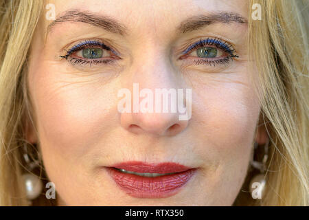 Close up 7/8 Portrait von eine attraktive blonde Frau mit blauen Augen und trug Make-up in die Kamera starrte mit geöffneten Lippen Stockfoto