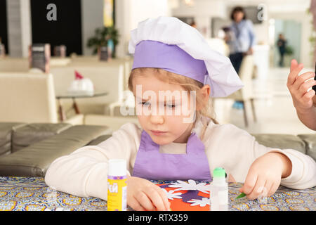 Kinder lernen kleine Kuchen mit Sahne zu kochen. Machen einen Urlaub Karte für Mama. März 8. Stockfoto