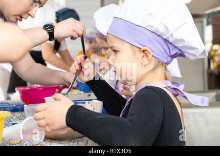 Kinder lernen kleine Kuchen mit Sahne zu kochen. Machen einen Urlaub Karte für Mama. März 8. Stockfoto