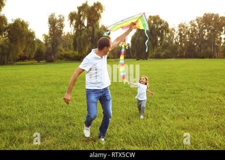 Glückliche Familie Vater und Kind laufen auf Wiese mit einem Drachen im Sommer auf der Natur Stockfoto