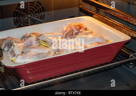 Leckere hausgemachte Braten mit Huhn und Kartoffeln, rohe Zutaten in einem keramischen Pfanne im heißen Ofen ein Abendessen mit der Familie Stockfoto