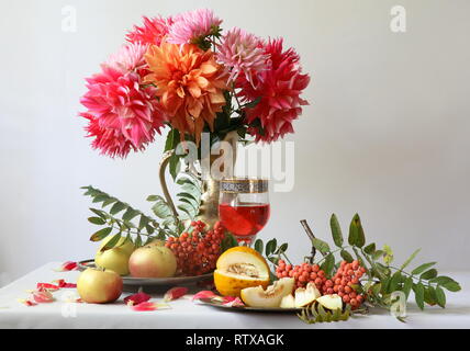 Noch immer leben mit einem Bouquet von Dahlien auf einen weißen Hintergrund mit Früchten Stockfoto