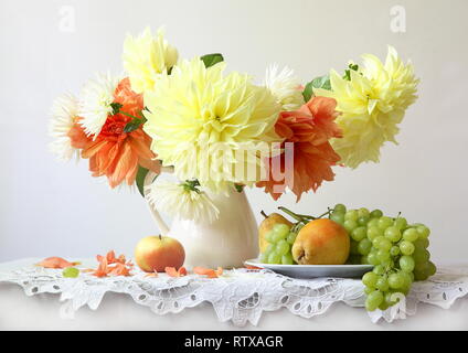 Noch immer leben mit einem Bouquet von Dahlien auf einen weißen Hintergrund mit Früchten Stockfoto