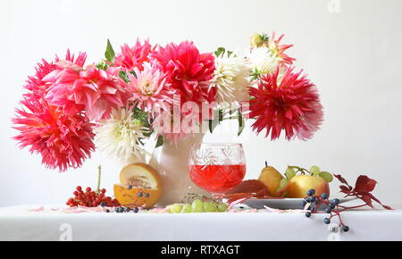 Noch immer leben mit einem Bouquet von Dahlien auf einen weißen Hintergrund mit Früchten Stockfoto