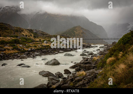 Ein Blick auf eine von drei Hängebrücken der Hooker Valley an einem bewölkten, Moody Tag. Das Tal ist im Mount Cook/Aoraki Nationalpark entfernt. Stockfoto