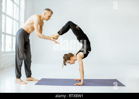 Junge Frau Yoga mit erfahrenen Senior Trainer in den weißen geräumige Studio Stockfoto