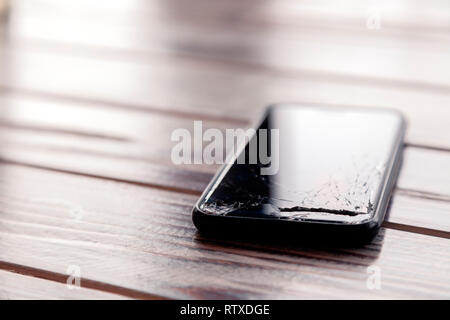 Сloseup BlackBerry-Smartphone mit ein zerbrochenes Display Glas liegen auf Holztisch. Konzept der Drop phone, gebrochen, Gadget, Elektronik Reparatur, Pech, cre Stockfoto