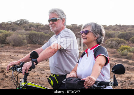 Fröhliche kaukasischen Erwachsener senior Paar mit Mountainbike, gesunden Sport outdoor Freizeit zusammen - alte Menschen genießen ältere Reiten in t Stockfoto