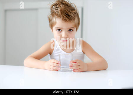 Nett lächelnden Jungen mit Glas Wasser auf einem weißen Hintergrund. Stockfoto