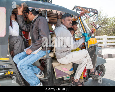 Indische Menschen reisen in einem überfüllten Tuktuk auf einer Landstraße in Uttar Pradesh. Überfüllte tuktuks sind ein alltäglicher Anblick auf den Straßen in Indien. Stockfoto