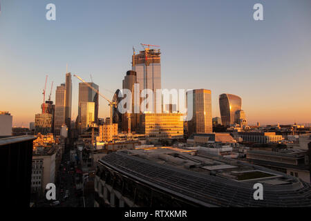 Eine dramatische Stadt London Skyline mit den Hochhäusern gebadet in goldenem Licht Stockfoto