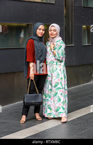 Junge Malaysische Frauen für ein Foto, traditionelles Kleid vs Casual im westlichen Stil, Pavilion Mall, Bukit Bintang, Kuala Lumpur, Malaysia posieren. Stockfoto