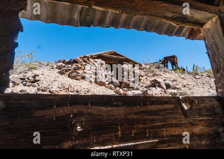 Ein Blick aus dem Fenster einer Ruine zu einem Stein Struktur und einen hohen Bergbau Struktur. Den Inyo Mine Ruinen waren ein Teil der Echo-Lee Bergbau distric Stockfoto