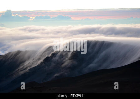 Wolken über einem Berg Rand auf dem Gipfel des Haleakala Vulkan bei Sonnenaufgang, Maui, Hawaii, USA Stockfoto