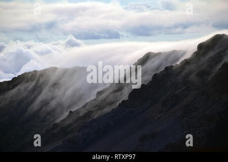 Wolken über einem Berg Rand auf dem Gipfel des Haleakala Vulkan bei Sonnenaufgang, Maui, Hawaii, USA Stockfoto