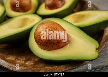 Nahaufnahme Foto von Avocado Hälften auf Holz geschnitzte Schale, Detail auf den braunen Samen/Grube. Stockfoto
