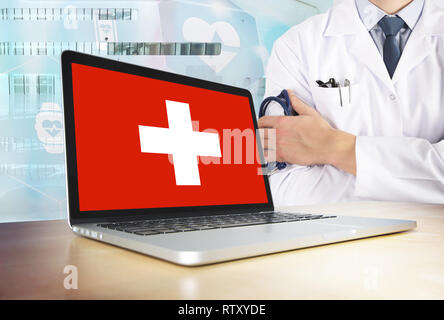 Schweiz Gesundheitswesen in tech Thema. Schweizer Fahne auf dem Computer angezeigt. Arzt stehend mit Stethoskop im Krankenhaus. Und Blockchai Cryptocurrency Stockfoto