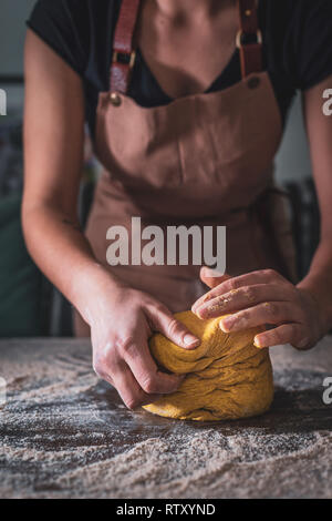 Frau Koch Schürze tragen kneten den Teig von Hand in Bäckerei Stockfoto
