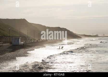 Helle Frühling Nachmittag an Saltburn-by-the-Sea, North Yorkshire, England. Zwei Surfer im Wasser stand. Stockfoto