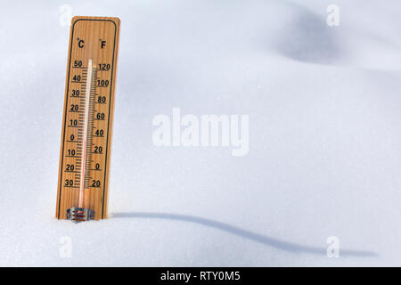 Holz- thermometer im Schnee, Sonne casting curvy Schatten, rote Spalte mit 0 Grad Celsius. Winter/Schnee kommen. Stockfoto