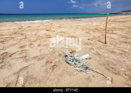 Perfekte leer unberührten Strand, kleine Haufen Müll (tangled Kunststoff Seile) auf feinem Sand, mit ruhigem Meer im Hintergrund. Ozean littering Konzept. Karpass, N Stockfoto