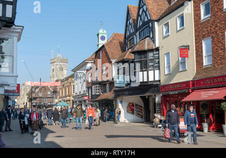 High Street, Salisbury, Wiltshire, England UK. Februar 2019. Käufer an der High Street in der Nähe der Eingang zum alten George Mall. Kirche Turm Stockfoto